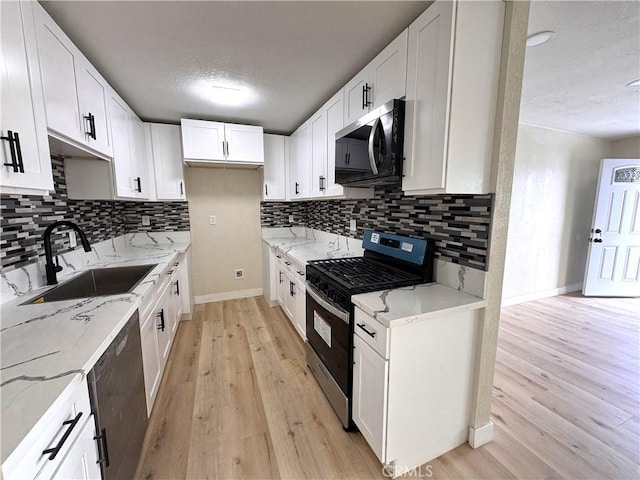 1716 Paloma St, Barstow, CA 92311 - kitchen with appliances with stainless steel finishes, a sink, light wood-style flooring, light stone countertops, and a textured ceiling