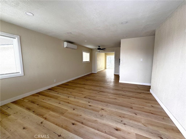 1716 Paloma St, Barstow, CA 92311 - spare room featuring an AC wall unit, baseboards, wood finished floors, a ceiling fan, and a textured ceiling