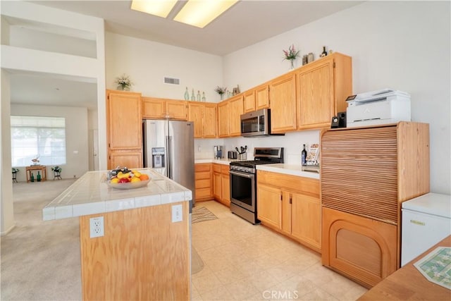831 Kilmarnock Way, Riverside, CA 92508 - kitchen with stainless steel appliances, tile counters, light brown cabinets, visible vents, and a towering ceiling