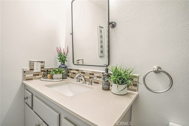bathroom featuring vanity, tasteful backsplash, and a textured wall