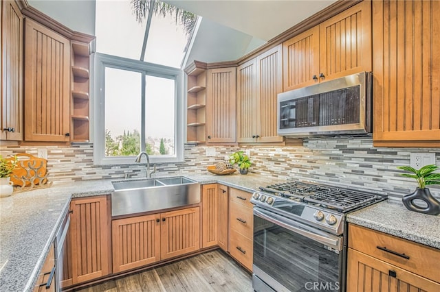 kitchen with appliances with stainless steel finishes, tasteful backsplash, open shelves, a sink, and light wood-style floors