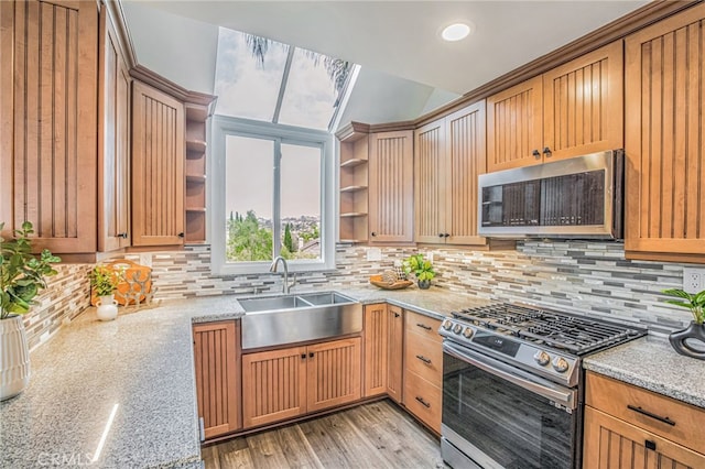 kitchen featuring appliances with stainless steel finishes, tasteful backsplash, open shelves, a sink, and light stone counters