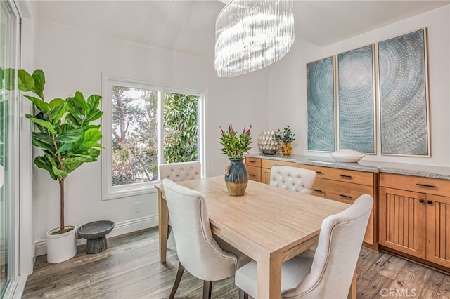 dining area with light wood-style floors, baseboards, and an inviting chandelier