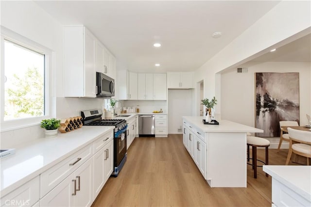 781 E Navilla Pl, Covina, CA 91723 - kitchen featuring appliances with stainless steel finishes, light wood finished floors, a breakfast bar area, and white cabinets
