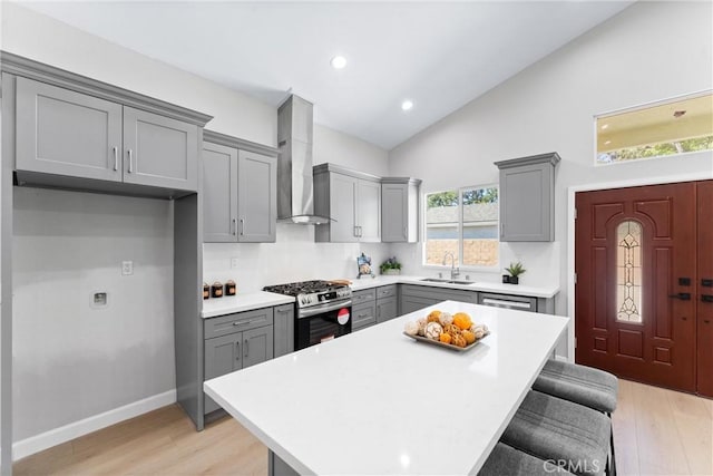 17841 Buena Vista Ave, Yorba Linda, CA 92886 - kitchen featuring gray cabinetry, gas stove, wall chimney exhaust hood, light wood finished floors, and light countertops