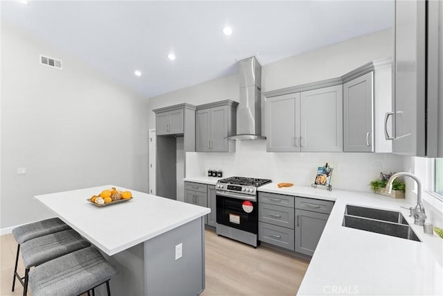 17841 Buena Vista Ave, Yorba Linda, CA 92886 - kitchen featuring gas range, wall chimney exhaust hood, gray cabinets, a kitchen breakfast bar, and light countertops