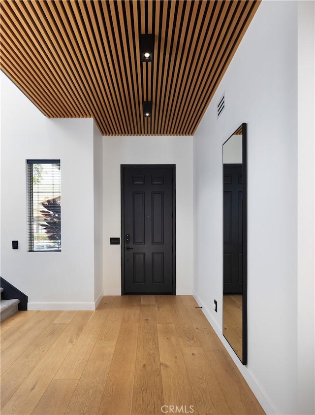 foyer entrance with baseboards, visible vents, light wood finished floors, and stairs