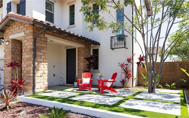 exterior space with stone siding, a tiled roof, stucco siding, and fence