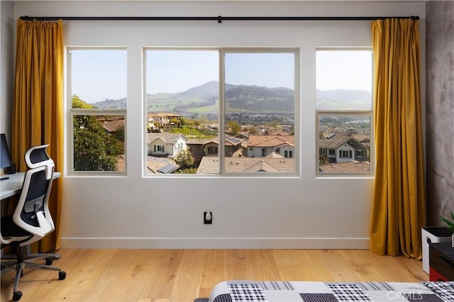 office featuring light wood-type flooring, plenty of natural light, baseboards, and a mountain view