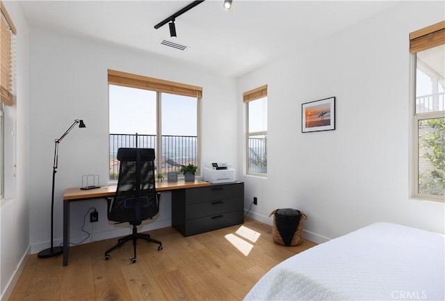bedroom featuring rail lighting, baseboards, visible vents, and light wood finished floors