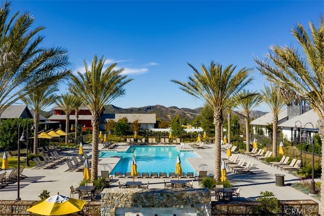 community pool with a mountain view, fence, and a patio