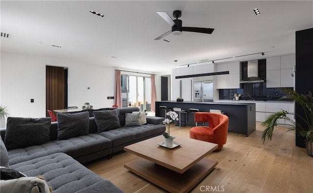 living room with light wood finished floors, a ceiling fan, and visible vents
