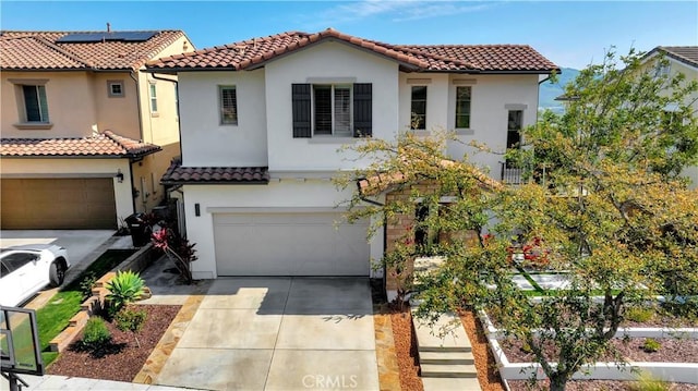 mediterranean / spanish house featuring an attached garage, a tile roof, driveway, and stucco siding