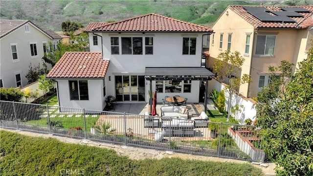 back of house with stucco siding, a tile roof, a patio area, and a fenced backyard