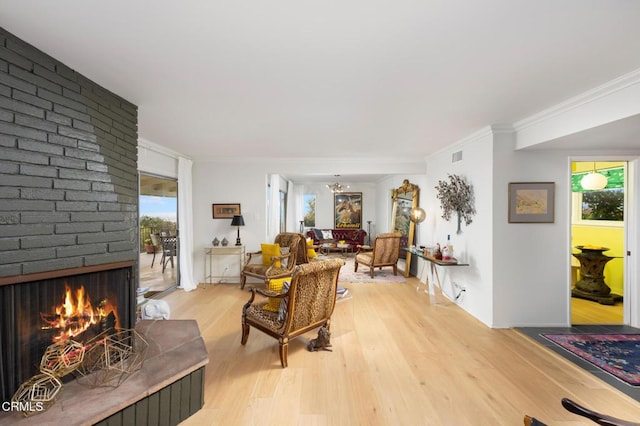 675 Mount Wilson Trl, Sierra Madre, CA 91024 - living area featuring light wood-style flooring, a brick fireplace, ornamental molding, and a chandelier