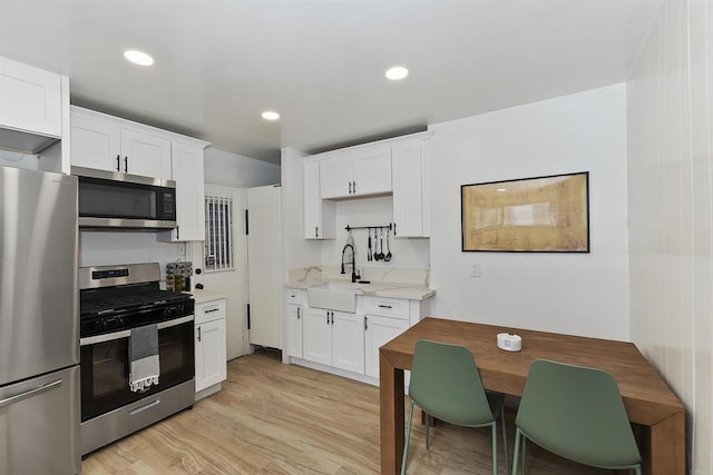 331 W Sherwood Blvd, Big Bear City, CA 92314 - kitchen featuring light wood finished floors, appliances with stainless steel finishes, white cabinetry, a sink, and light stone counters