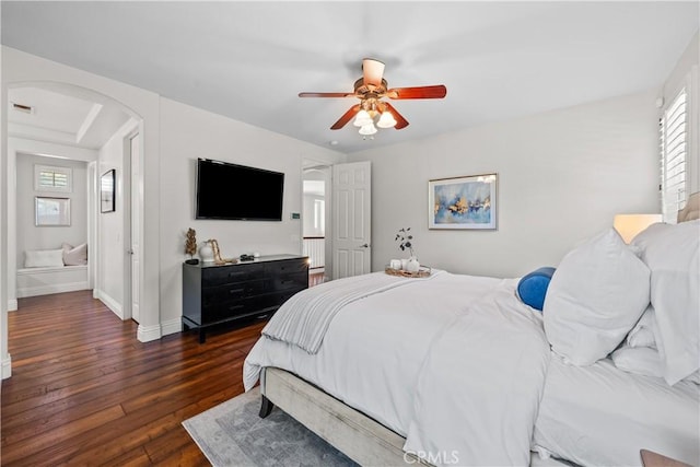 bedroom featuring arched walkways, multiple windows, dark wood finished floors, and baseboards