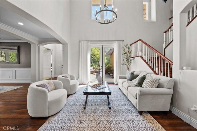 living area featuring dark wood-type flooring, a chandelier, stairway, ornamental molding, and french doors