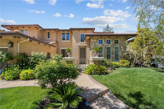 mediterranean / spanish-style house featuring a front lawn, stone siding, stucco siding, and a tile roof
