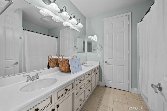 full bath with double vanity, marble look tiles, and baseboards