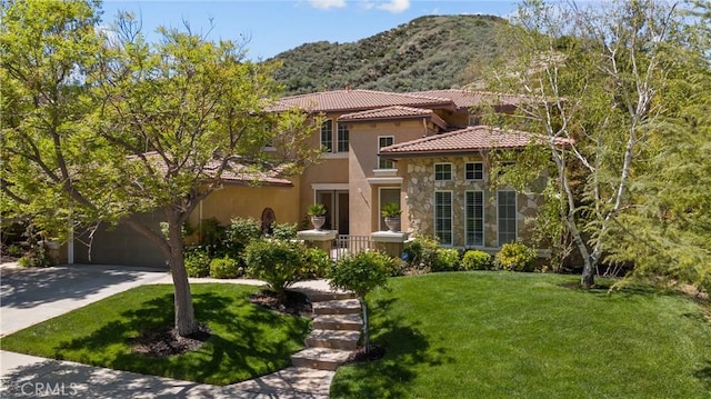 mediterranean / spanish house featuring stone siding, a tile roof, a mountain view, and a front lawn