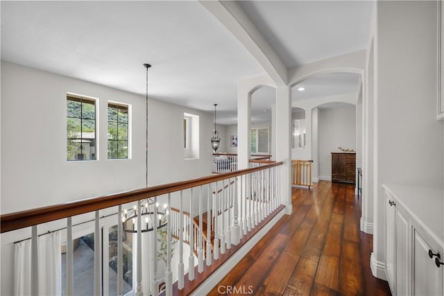 corridor with dark wood-style floors, recessed lighting, an upstairs landing, a chandelier, and arched walkways