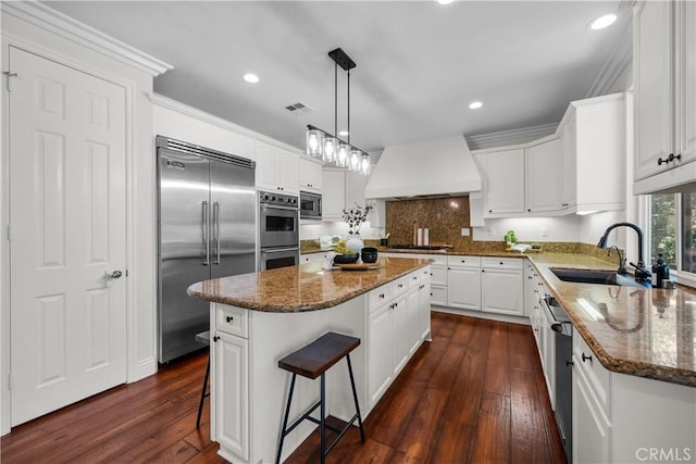 kitchen with built in appliances, a sink, premium range hood, a kitchen island, and dark wood-style floors