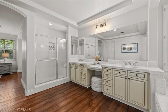 full bath featuring a tray ceiling, a stall shower, vanity, and wood-type flooring