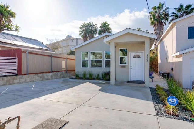 view of front of home featuring a patio area, stucco siding, and fence