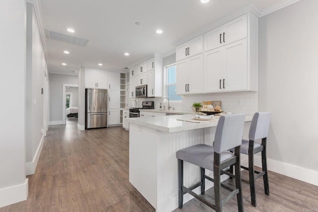 kitchen with a sink, white cabinets, a peninsula, and stainless steel appliances