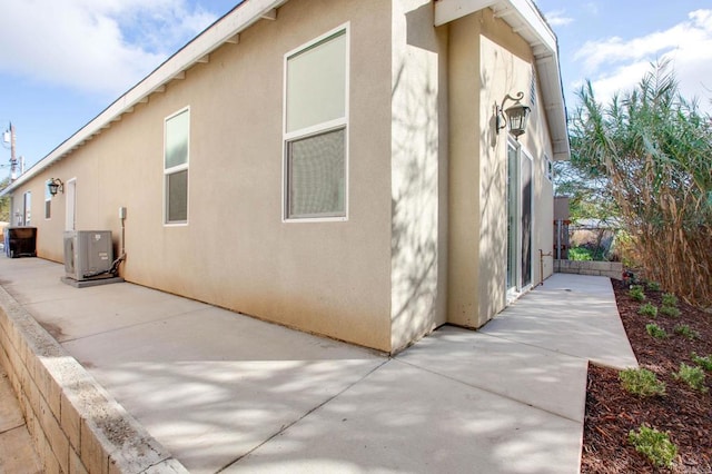 view of property exterior with central air condition unit, stucco siding, and a patio area