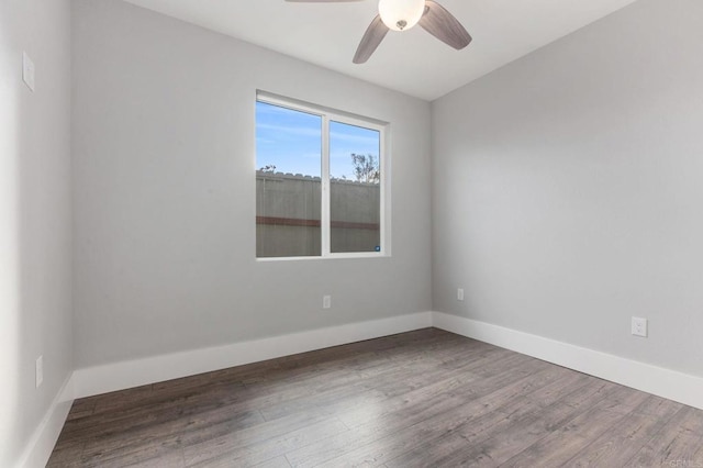 spare room featuring wood finished floors, a ceiling fan, and baseboards