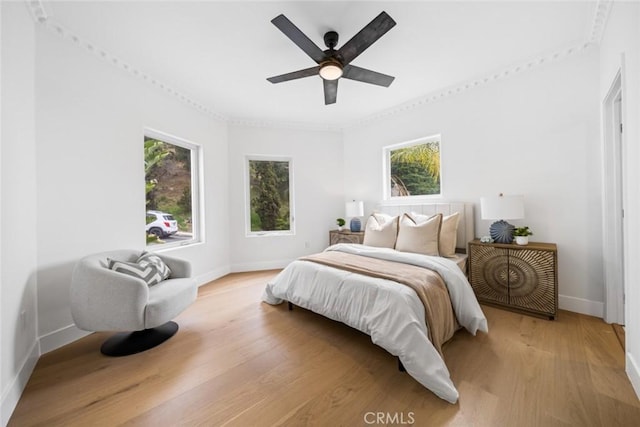 bedroom featuring multiple windows, ceiling fan, light wood-type flooring, and baseboards