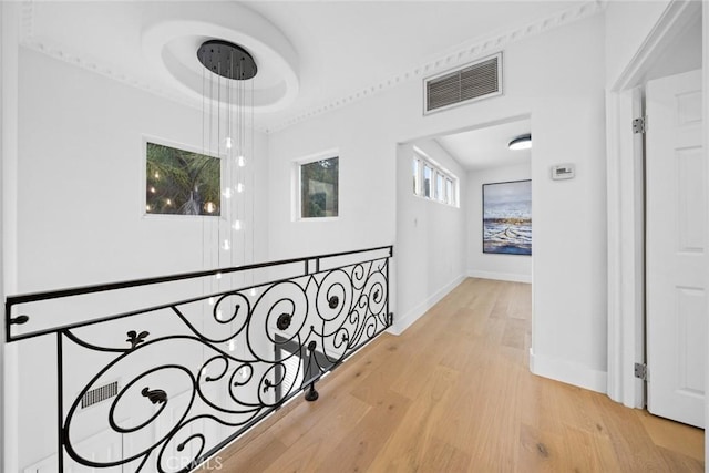 corridor with baseboards, visible vents, and light wood-style flooring