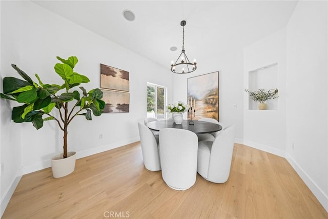 dining area featuring an inviting chandelier, light wood-style floors, and baseboards