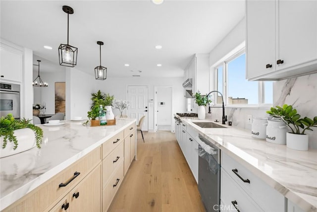 kitchen with recessed lighting, light wood finished floors, a sink, stainless steel appliances, and light stone counters