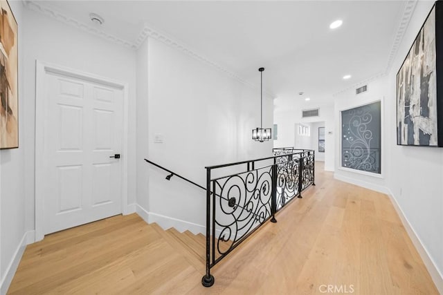staircase featuring a chandelier, visible vents, baseboards, ornamental molding, and wood finished floors