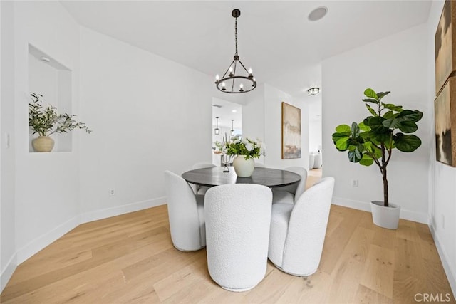 dining area with an inviting chandelier, light wood finished floors, and baseboards