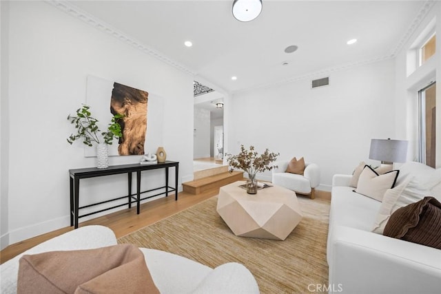 living room featuring visible vents, light wood-style flooring, and crown molding
