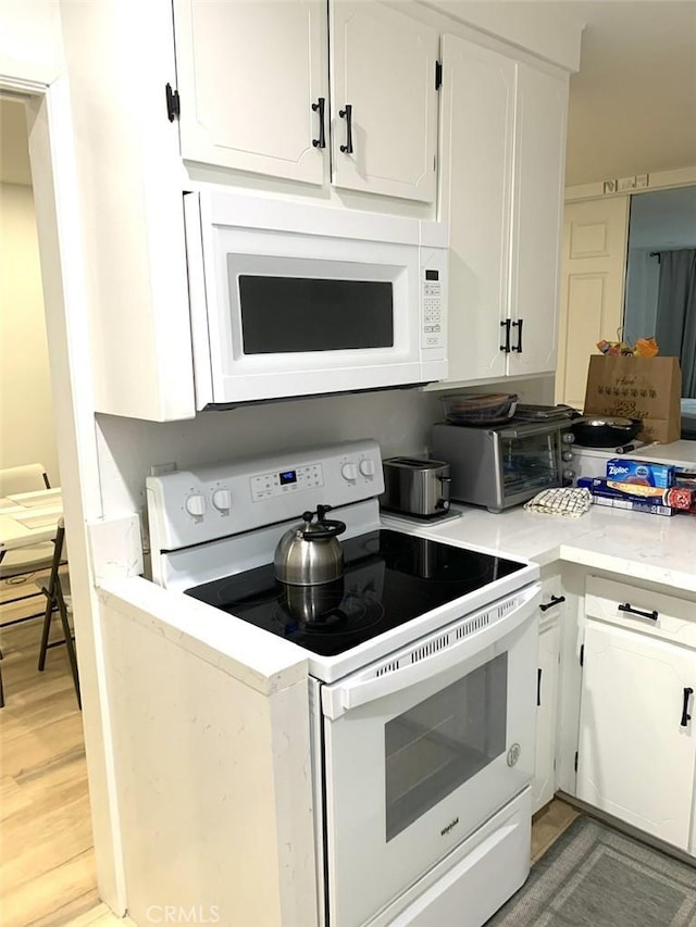 1250 S Beverly Glen Blvd Unit 205, Los Angeles, CA 90024 - kitchen with white appliances, white cabinets, light wood-type flooring, and light stone counters