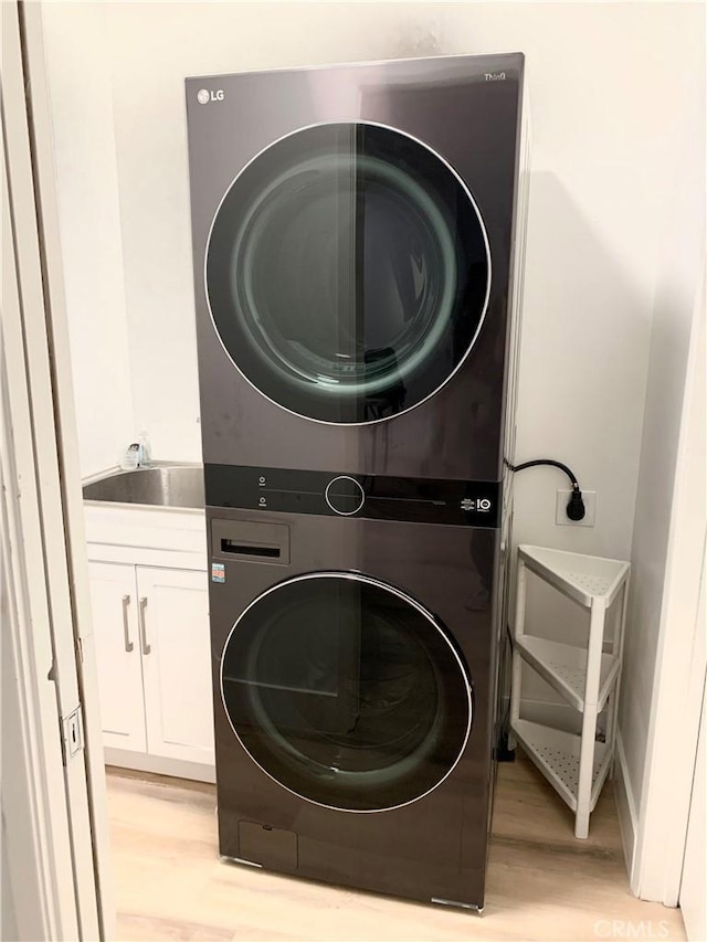 1250 S Beverly Glen Blvd Unit 205, Los Angeles, CA 90024 - washroom featuring stacked washing machine and dryer, light wood-type flooring, and cabinet space