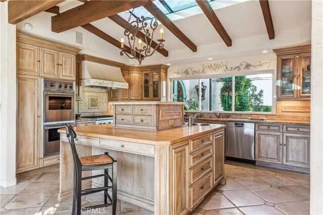 kitchen featuring lofted ceiling with beams, premium range hood, a center island with sink, tasteful backsplash, and appliances with stainless steel finishes