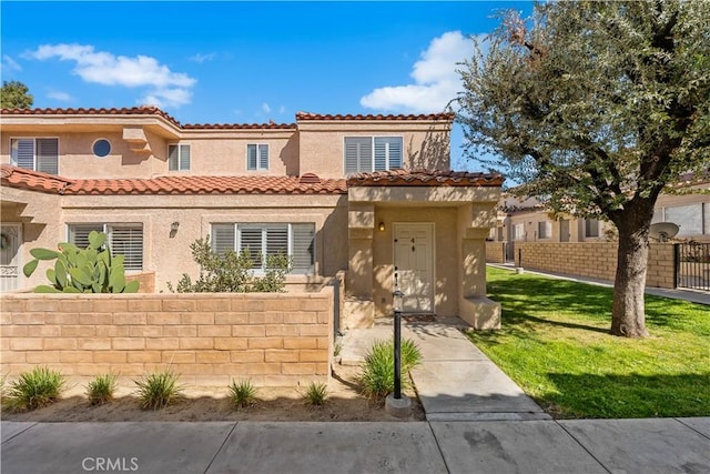 view of front facade featuring a tiled roof, stucco siding, a gate, and a fenced front yard