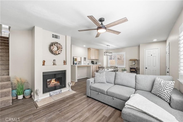 living room featuring visible vents, wood finished floors, stairway, a ceiling fan, and a multi sided fireplace