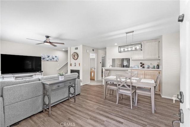 living room featuring a ceiling fan, baseboards, light wood finished floors, and recessed lighting
