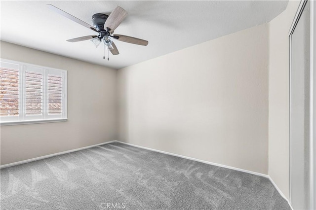 empty room featuring baseboards, carpet flooring, and a ceiling fan