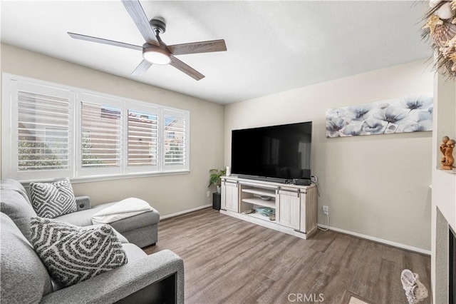 living room featuring baseboards, wood finished floors, and ceiling fan