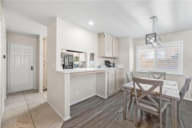 kitchen featuring light countertops, stainless steel fridge, baseboards, light tile patterned flooring, and pendant lighting