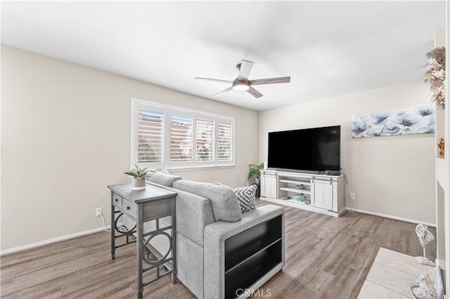 living room with baseboards, wood finished floors, and a ceiling fan