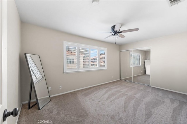 unfurnished bedroom with a closet, carpet flooring, visible vents, baseboards, and ceiling fan